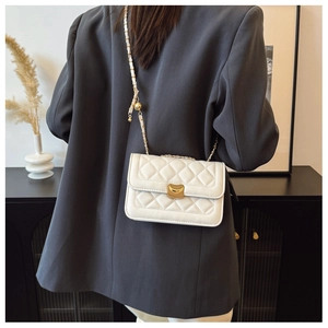 Detail of white quilted crossbody bag with golden crescent lock and leather chain strap