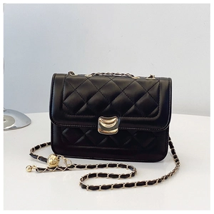 Close-up of quilted black leather texture with gold crescent lock and metal chain
