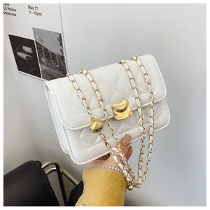 Detail of cream quilted crossbody bag featuring golden chain and adjustable metal ball