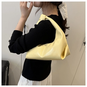 Dettaglio della borsa hobo giallo brillante con manico a nodo e pelle sintetica a pieghe