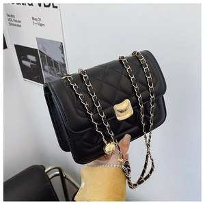 Detailed macro view of black quilted leather texture and gold metal chain strap on bag