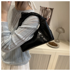 Detailed view of black patent leather hobo bag with a stylish knotted handle design
