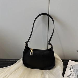 Elegant black lychee grain baguette shoulder bag with gold hardware on white fabric