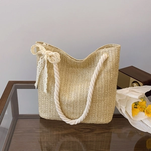 Handwoven straw tote bag with white cotton rope handles and lace bow for summer beach travel