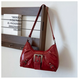 Macro shot of red vintage hobo bag with buckled straps and ruched faux leather detail