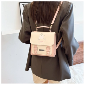 Detail eines rosa-weißen PU-Leder Mini-Rucksacks mit Cartoon-Print auf grauem Blazer