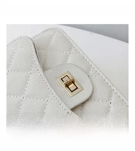 Close-up of golden rotary lock on white quilted leather bag with luxury texture