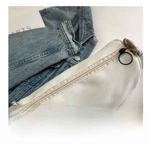 Detail of white nylon cylinder bag featuring colorful geometric jacquard wide shoulder strap