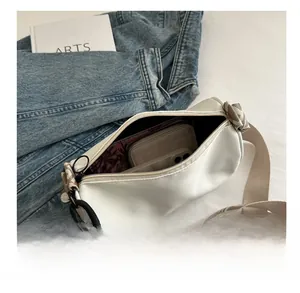 Detail view of white canvas crossbody bag showing large capacity for phone and wallet