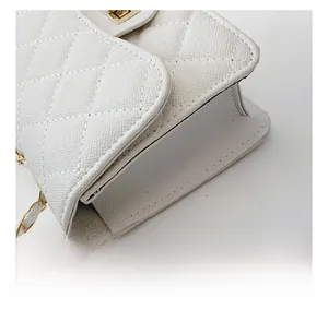 Detail showing white quilted leather texture, golden twist lock and chain strap on bag