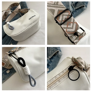 Detail view of white canvas Boston bag with ethnic woven strap and braided zipper puller