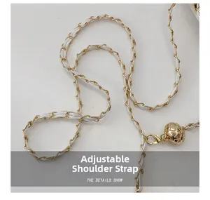Close-up of adjustable white leather and gold metal chain strap with sphere buckle