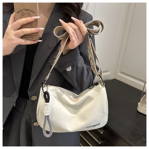 Close-up of white canvas Boston bag featuring khaki geometric jacquard strap and pendant