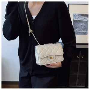 Detail of white quilted leather flap bag with gold ball chain strap and turn-lock