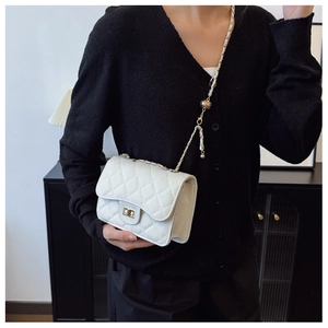 Close-up of a white quilted crossbody bag with gold chain strap and metal turn-lock closure
