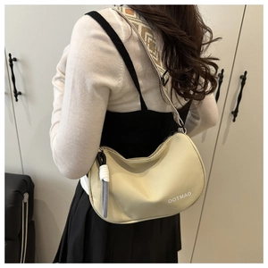 Close-up of cream half-moon bag featuring a geometric jacquard strap and letter print