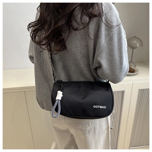 Detail of minimalist black nylon crossbody bag with wide patterned strap and rope zipper pull