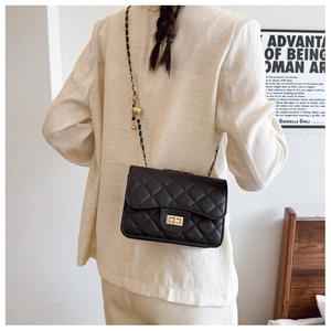 Detail of black quilted leather chain bag with adjustable gold ball buckle and lock