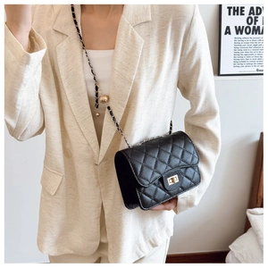 Détail d'un sac bandoulière matelassé noir avec chaîne dorée et bille de réglage