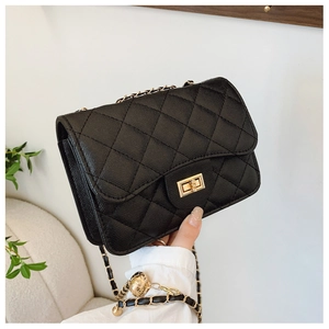 Close-up of quilted black crossbody bag with golden twist lock and woven chain strap