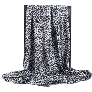 Elegant black and white leopard print satin square silk scarf on a display frame