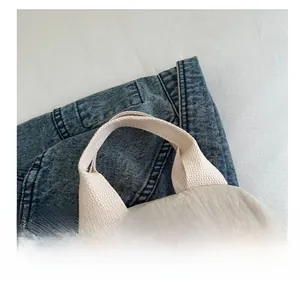 Detailed close-up of thickened woven handle and light grey textured fabric on the tote bag