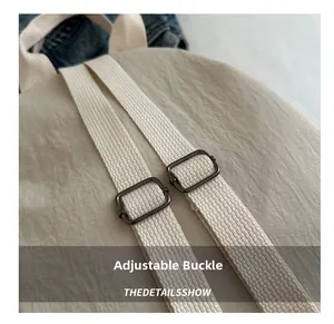 Detail view of adjustable shoulder straps with gunmetal buckles on a beige nylon bag