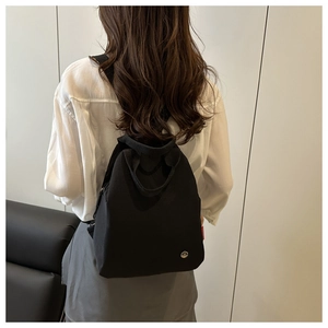 Detailed view of the black minimalist backpack with metallic logo and red brand label