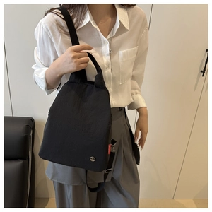 Detail of black nylon tote bag featuring metallic logo and red fashion side label