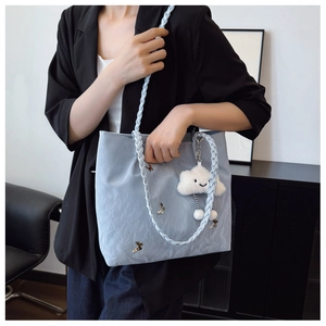 Detail of light blue tote bag with braided strap, golden butterfly and cloud charm