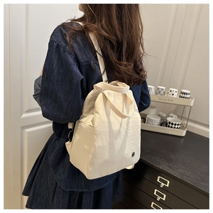 Détail du sac à dos blanc cassé avec texture plissée et boucles métalliques réglables