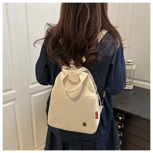 Close-up of cream canvas backpack featuring a red FASHION label and metal detail