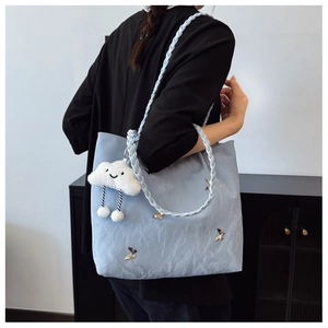 Side view of light blue nylon tote bag with butterfly charm and white cloud plush toy