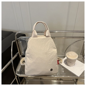 Gros plan d'un sac à dos en nylon crème montrant sa texture et son étiquette