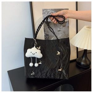 Detail of black backpack featuring silver metal butterflies and a white cloud plush charm