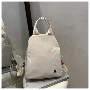 Detail of minimalist beige nylon backpack with red fashion tag and round logo hardware