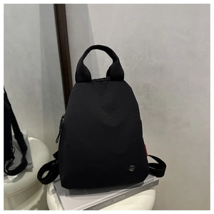 Détail d'un sac à dos en nylon noir en forme de goutte avec logo et étiquette rouge