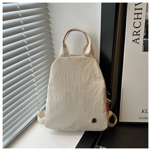 Détail du sac à dos en nylon beige avec tissu texturé et étiquette rouge latérale