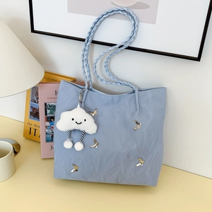 Light blue tote bag with gold butterfly accent and braided handles on a minimalist desk