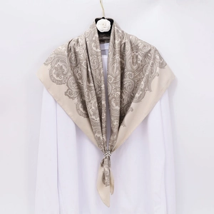 Luxurious beige paisley silk scarf draped over a white shirt with camellia hanger decor