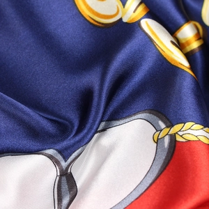 Detailed macro shot of satin scarf featuring gold chain and equestrian strap patterns