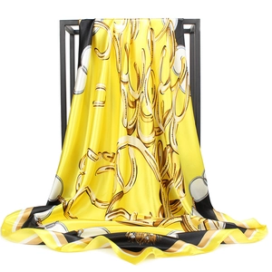 Close-up of yellow silk satin scarf with golden chain and equestrian buckle print