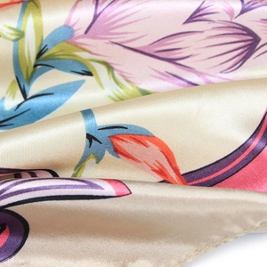 Close-up of silky satin fabric with tropical floral print in soft champagne tones