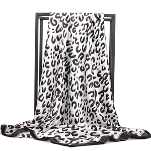 Fashionable leopard print satin silk scarf with black border on a minimalist rack