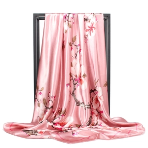 Carré en satin rose avec imprimé floral de magnolia blanc sur un support noir