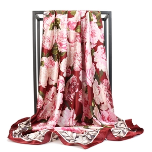 Detail of red floral satin scarf featuring pink flower print on a metal stand