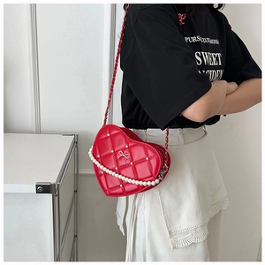 Detail of red heart-shaped crossbody bag with quilted pattern and pearl accents