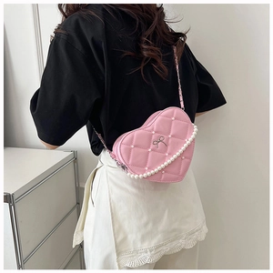 Close-up of pink heart-shaped bag with quilted pattern, pearls, and a metal chain strap