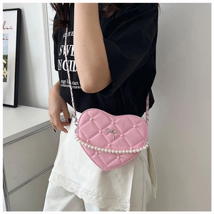 Close-up of pink heart-shaped bag featuring pearl trim and silver bow detail