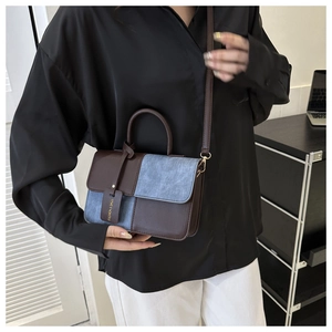 Detail van blauwe denim en bruin leren handtas met modieus label en bovenste handgreep